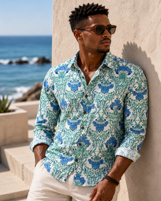 Man wearing a patterned shirt leaning against a wall with ocean view
