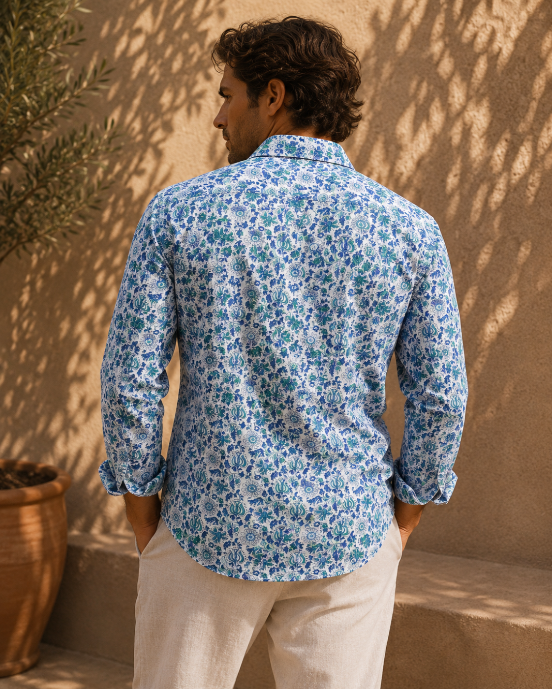 Man wearing a blue floral shirt against a beige wall
