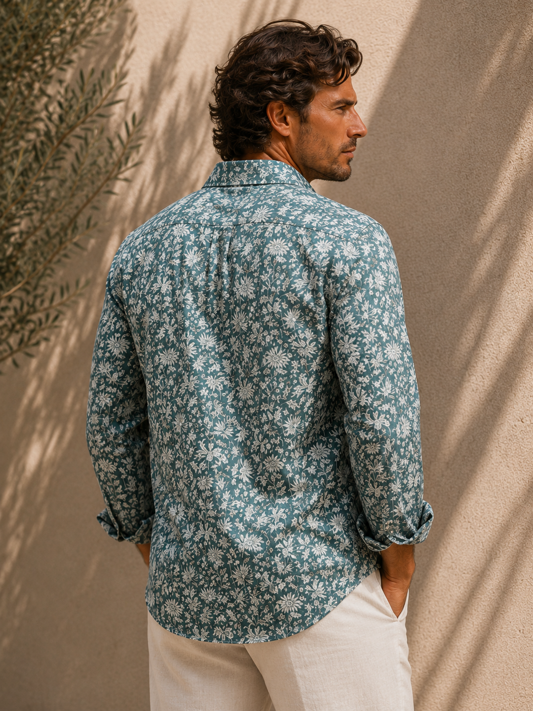 Man wearing a green gray floral shirt against a beige wall