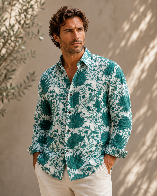 Man wearing a green floral patterned shirt against a beige wall.