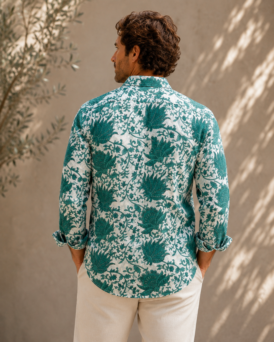 Man wearing a green and white patterned shirt against a beige wall.