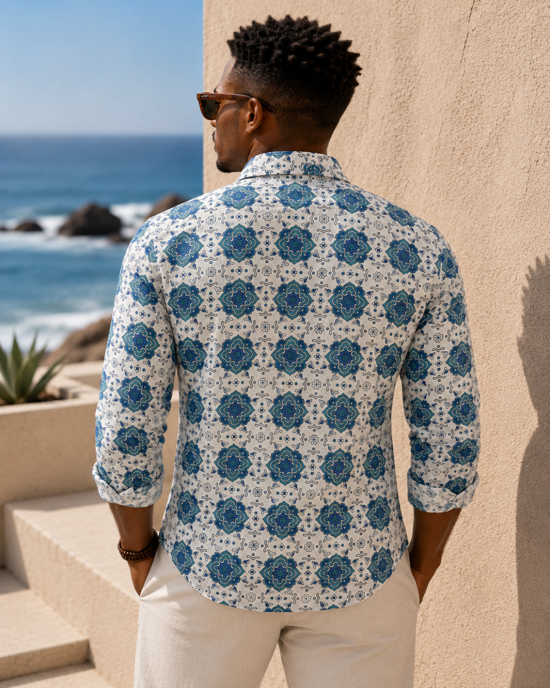 Man wearing a patterned shirt standing by a coastal scene