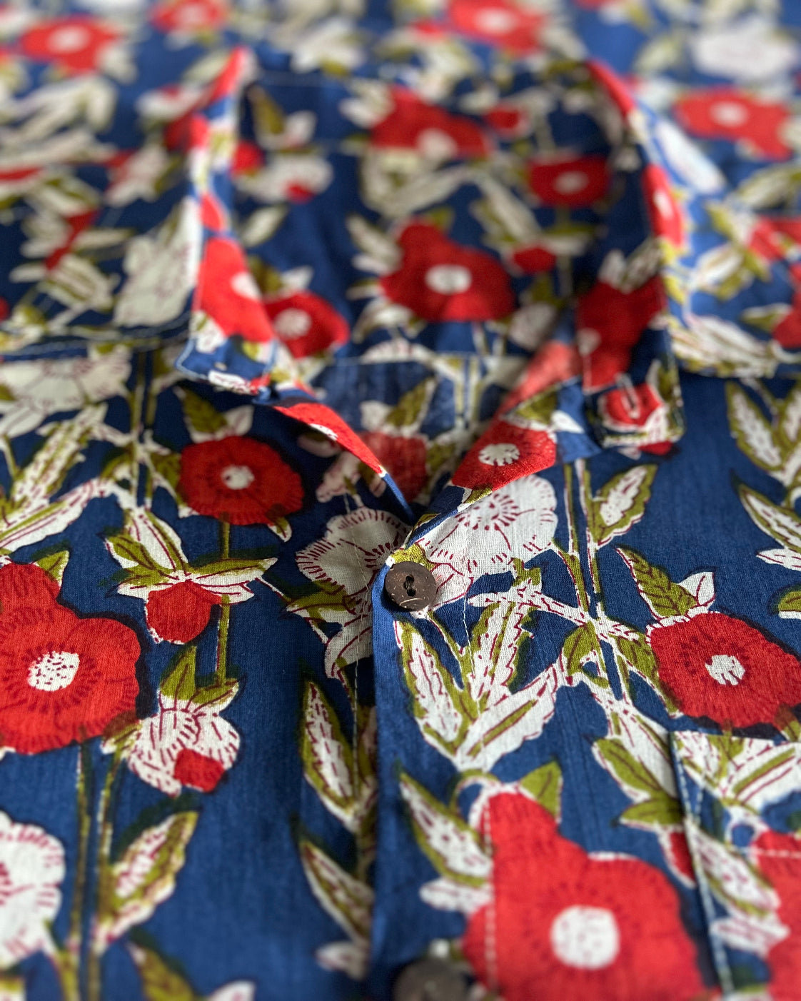 Close-up of a floral fabric with red, white, and blue flowers on a blue background.