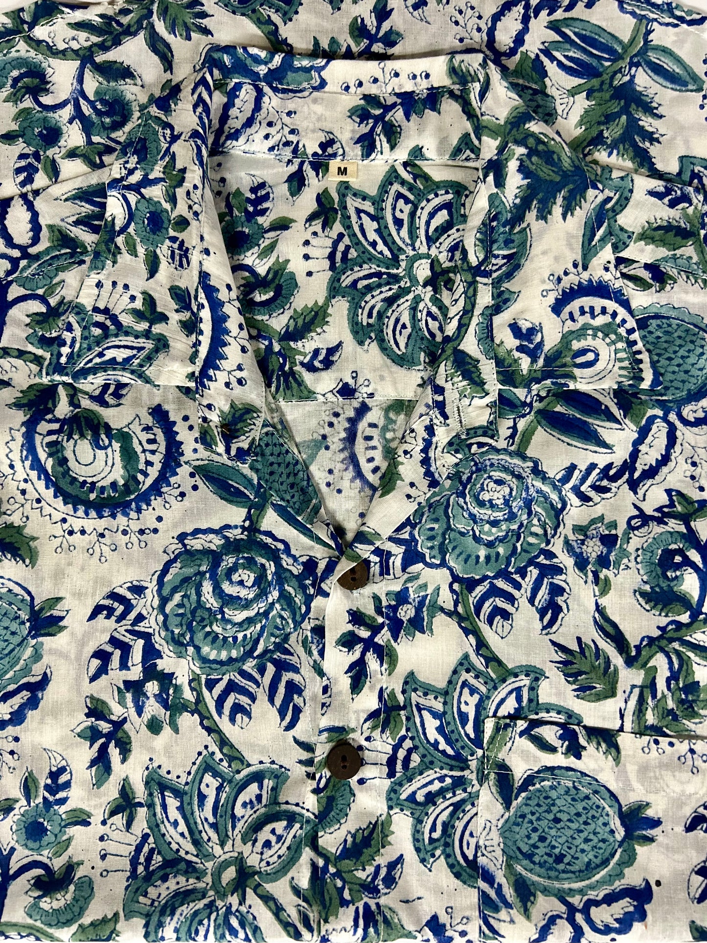 Close-up of a fabric with blue and green floral pattern on a white background